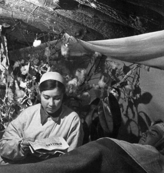 Фотография сестры милосердия, читающей газету раненому